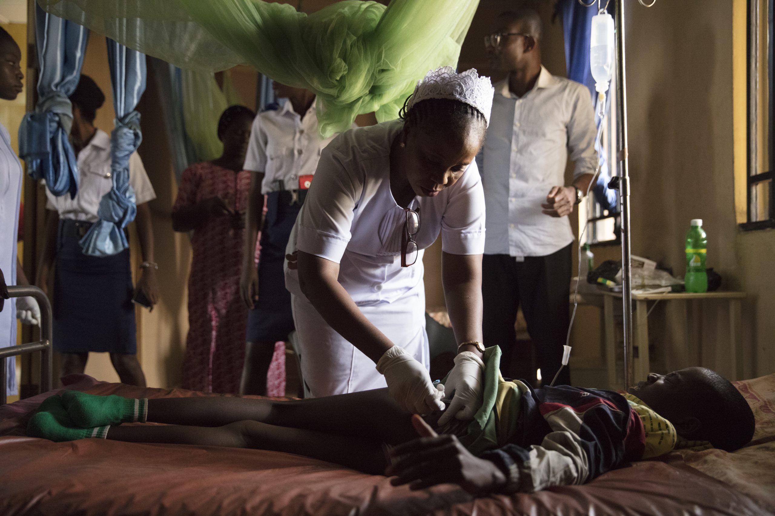 A doctor bends over a child in a bed